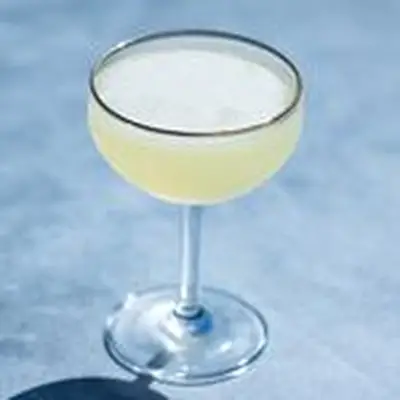 Tequila Daisy in a coupe glass with gold rim against a light blue background
