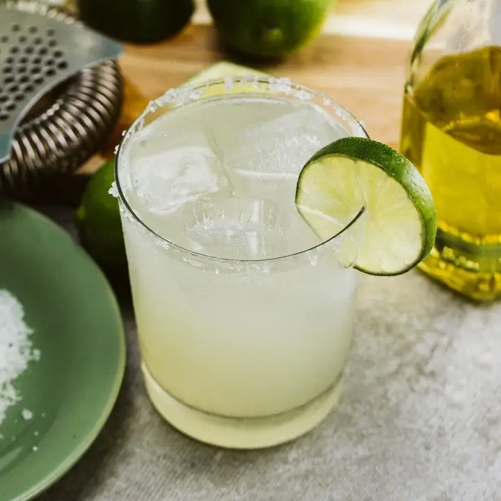 A Margarita in a salt-rimmed rocks glass garnished with a lime wheel