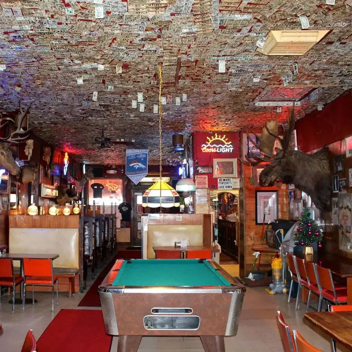 Shooting Star Saloon. The ceiling is covered in dollars bills and a pool table anchors the center of the small space
