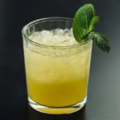 A yellow-hued Mai Tai on crushed ice garnished with a mint sprig