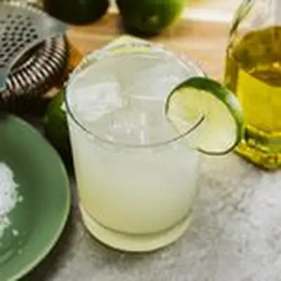 A Margarita in a salt-rimmed rocks glass garnished with a lime wheel