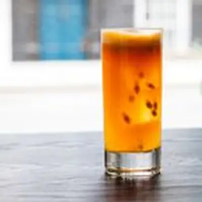 Aperitivo #1 cocktail in a highball glass with floating passion fruit seeds