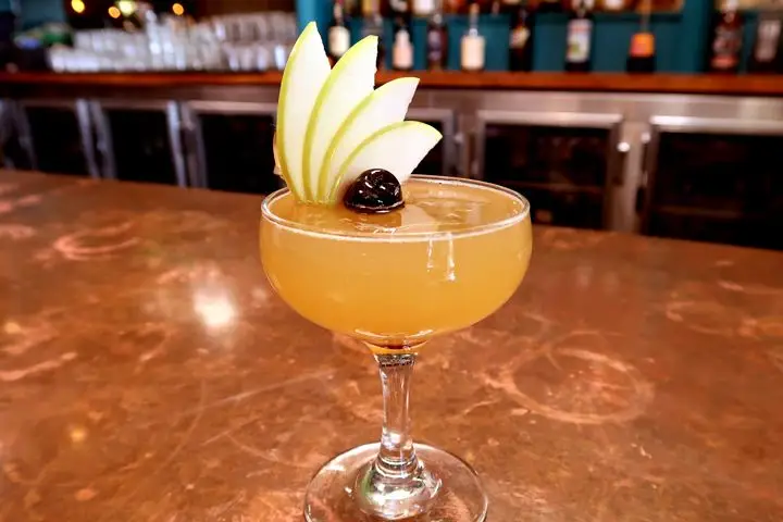 Nic’s on Beverly’s Appletini in a short-stemmed coupe glass garnished with a fan of green apple slices and a brandied cherry