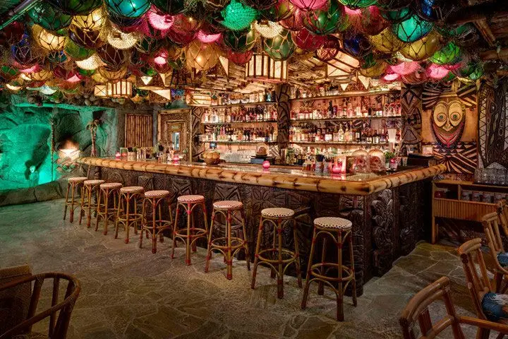 A wide-angle view of the bamboo and carved idol bar at False Idol with brightly colored lanterns scattered around the ceiling
