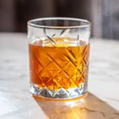 One Last Midnight cocktail in a crystal-cut rocks glass, served over one large ice cube