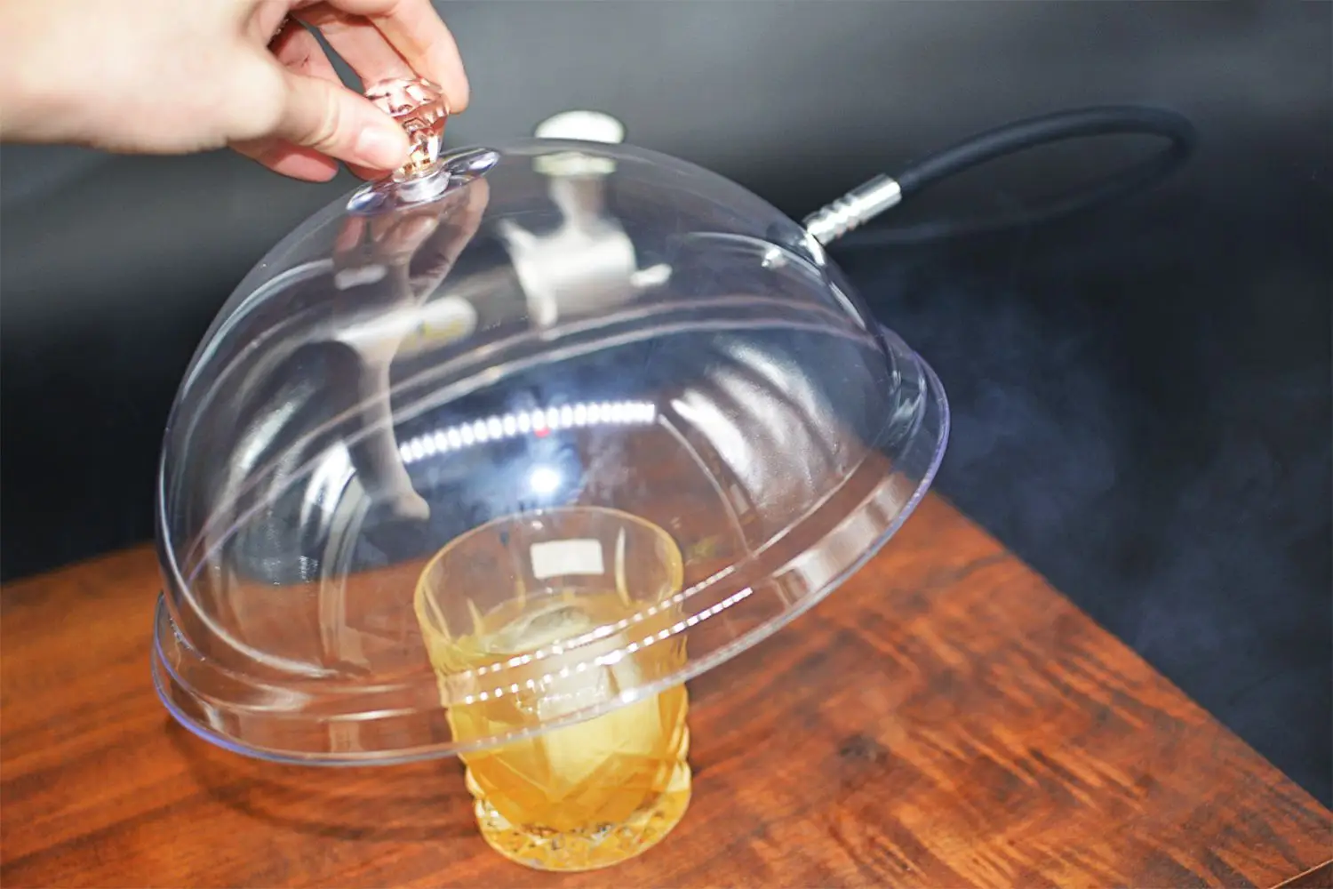 Hand placing Mitbak smoker over glass on wood board