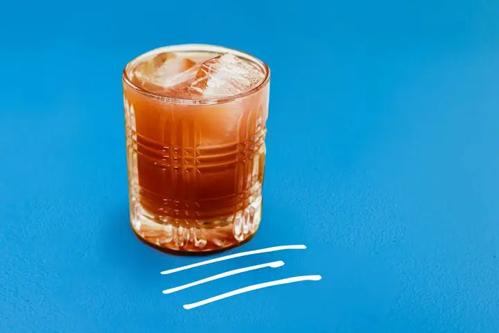 Photo illustration of red Port New York Sour in rocks glass on blue background with white hand-drawn lines