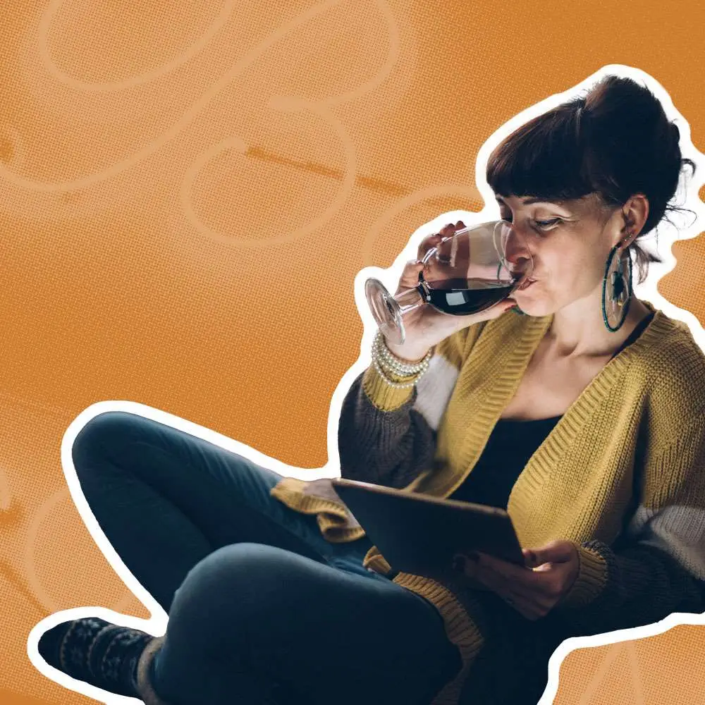Woman drinking red wine on an orange background