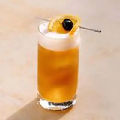 Singapore sling, light orange, in Collins glass, with white foam on top and cherry skewed with orange slice