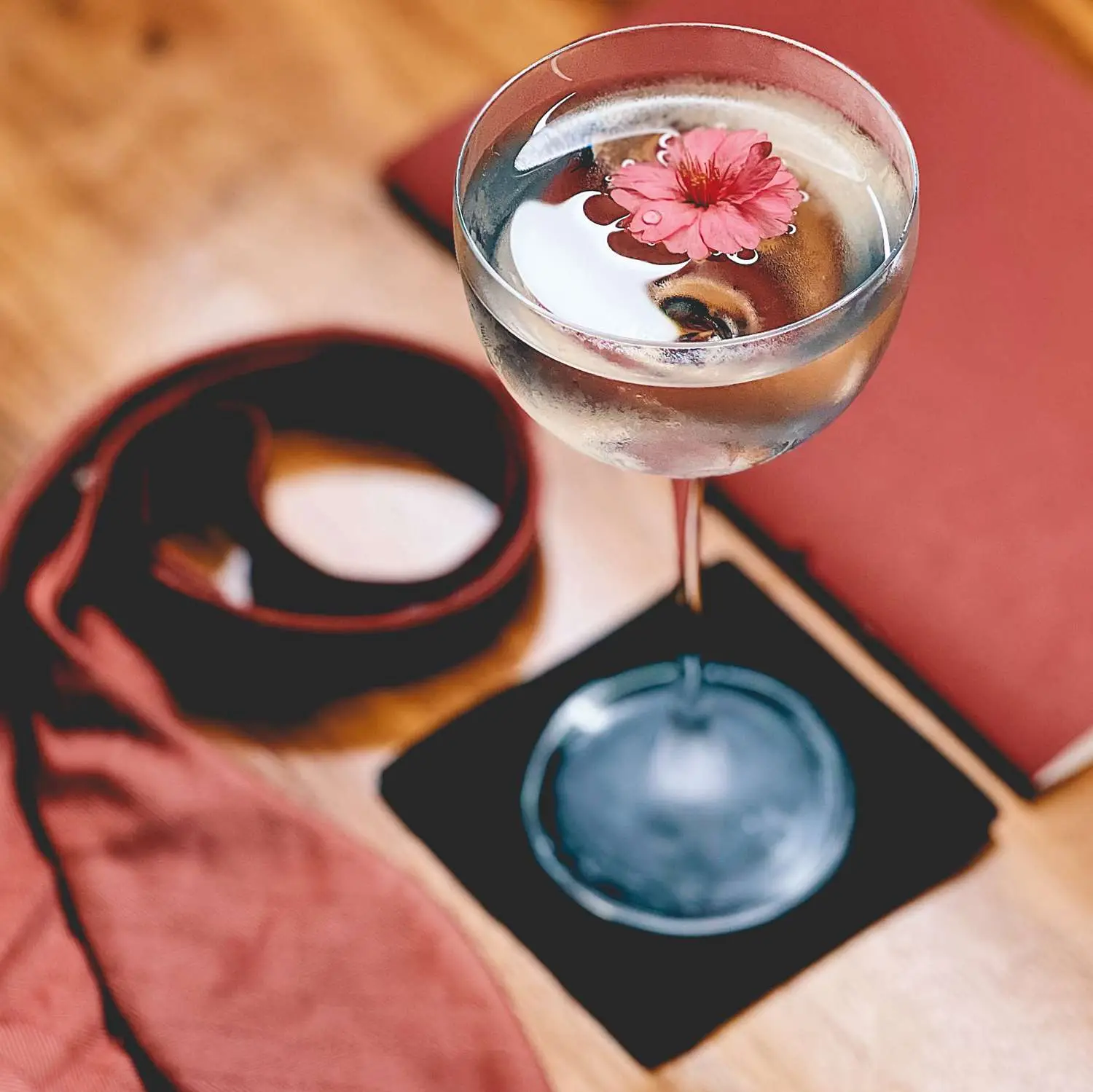The Cherry Five Ways cocktail in a coupe glass, on linen bar napkin, with flower garnish