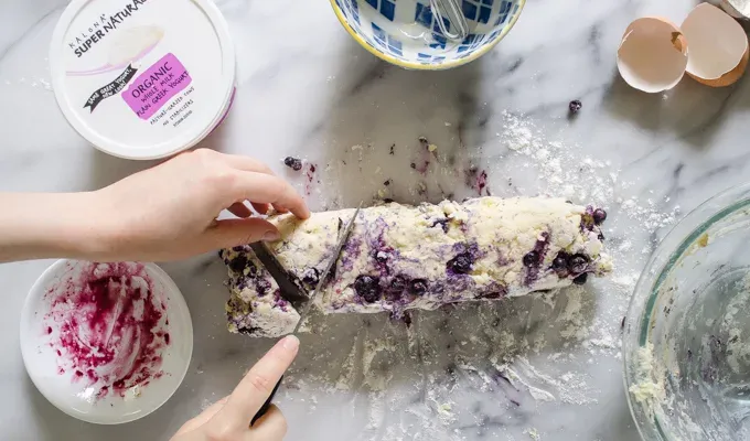 Slicing the dough into triangles with a knife.' title='Easy Blueberry Greek Yogurt Scones Recipe with Lemon