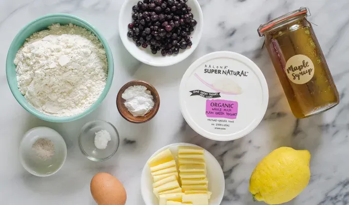 Ingredients for Greek yogurt scones from above on a marble surface.' title='Easy Blueberry Greek Yogurt Scones Recipe with Lemon
