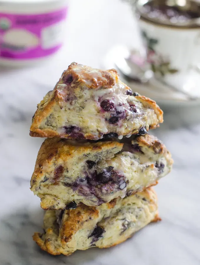 Stack of three scones on a plate drizzled with glaze.' title='Easy Blueberry Greek Yogurt Scones Recipe with Lemon