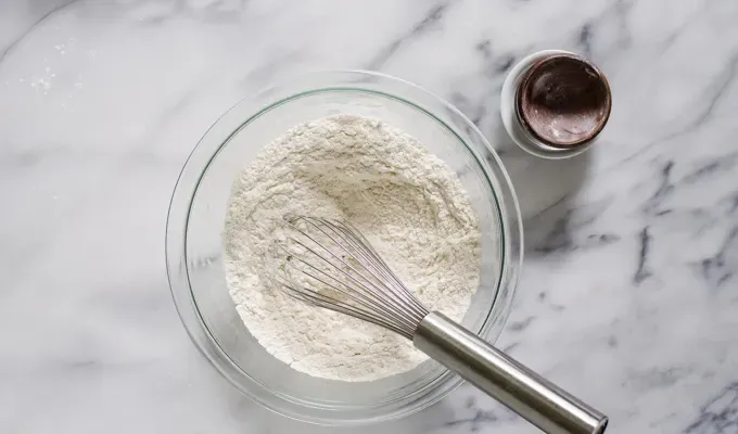 Dry ingredients in a bowl with a whisk.' title='Easy Blueberry Greek Yogurt Scones Recipe with Lemon