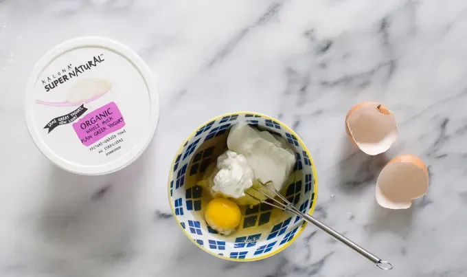 Greek yogurt maple syrup and and egg in a small blue bowl.' title='Easy Blueberry Greek Yogurt Scones Recipe with Lemon