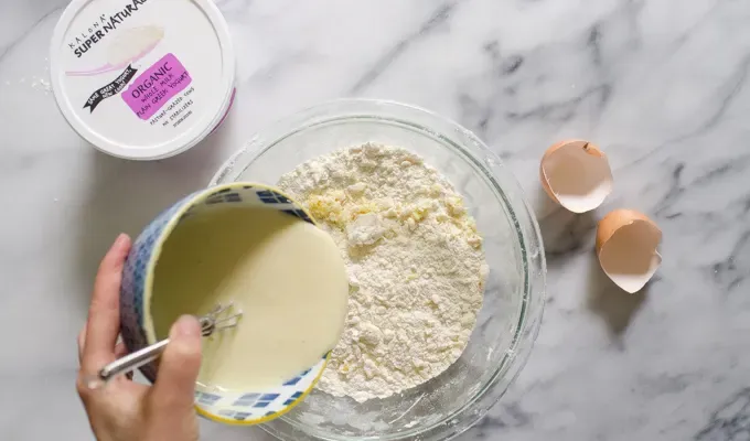 Pouring the wet ingredients into the dry ingredients.' title='Easy Blueberry Greek Yogurt Scones Recipe with Lemon