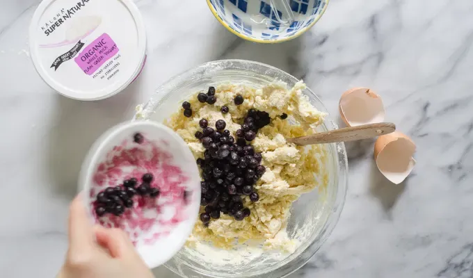 Pouring frozen wild blueberries into the dough.' title='Easy Blueberry Greek Yogurt Scones Recipe with Lemon