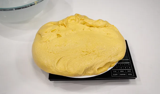 Placing the dough on a scale to weigh it.' title='Pumpkin Sourdough Dinner Rolls