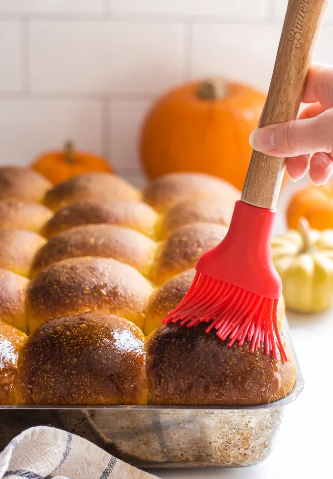 Brushing the tops of the rolls with melted butter.' title='Pumpkin Sourdough Dinner Rolls