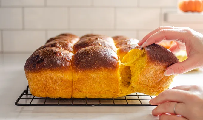 Pulling one of the rolls from the rest.' title='Pumpkin Sourdough Dinner Rolls