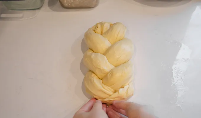 Pinching the ends of the braid to secure.' title='Sourdough Brioche