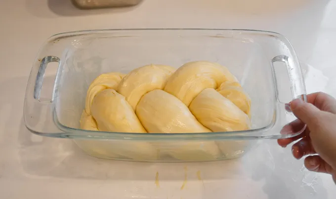 Tucking the sourdough brioche braid into the greased loaf pan.' title='Sourdough Brioche