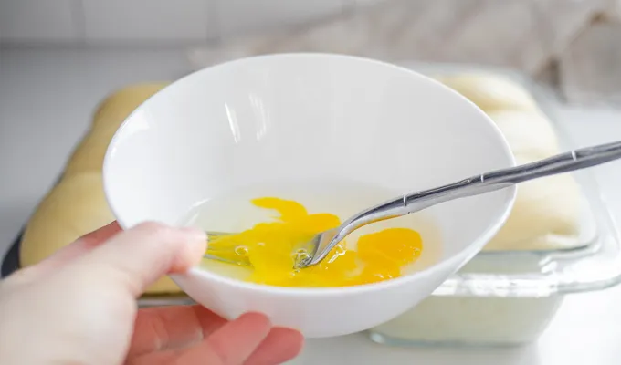 Whisking together an egg plus a tablespoon of water to brush on top of the loaf.' title='Sourdough Brioche