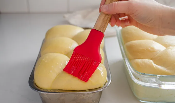 Brushing the top of the bun loaf with the egg wash.' title='Sourdough Brioche