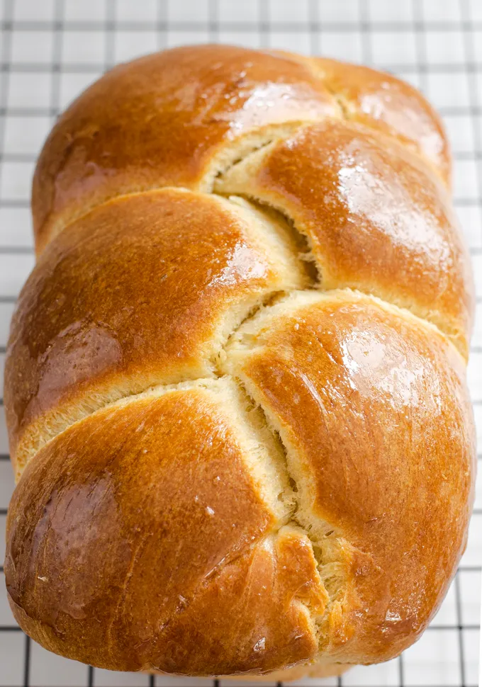 A loaf of sourdough brioche bread on a black wire cooling rack.' title='Sourdough Brioche