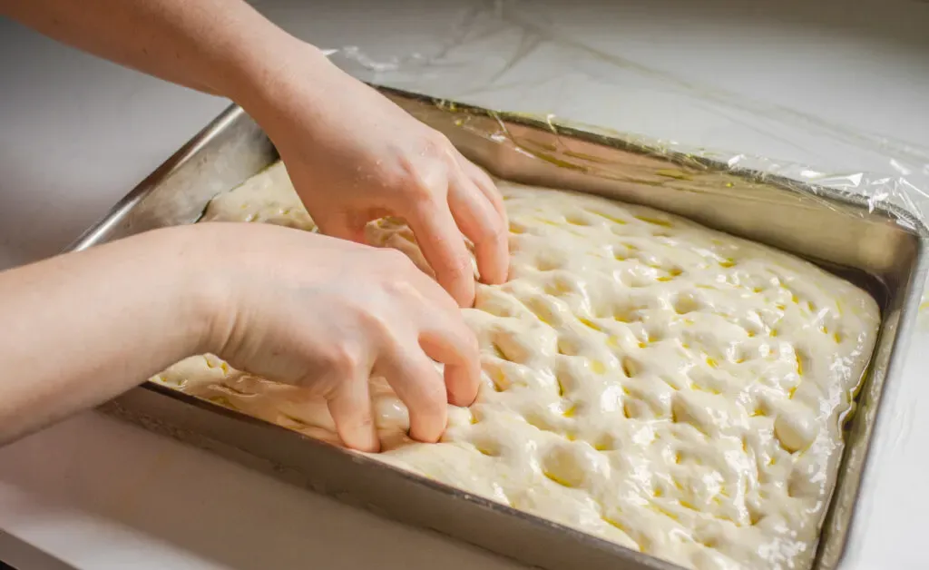 Dimpling the sourdough focaccia dough.' title='Sourdough Focaccia Recipe