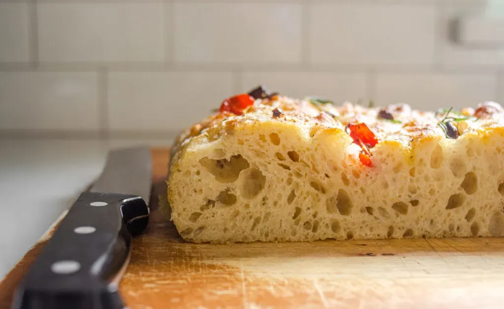 A side shot of a sliced piece of sourdough focaccia so you can see the open crumb.' title='Sourdough Focaccia Recipe