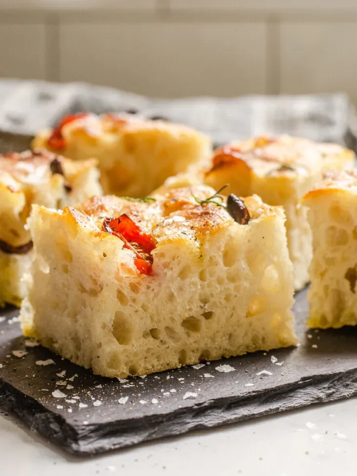 A side shot of a sliced piece of sourdough focaccia so you can see the open crumb.' title='Sourdough Focaccia Recipe