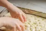 Dimpling the sourdough focaccia dough.' title='Sourdough Focaccia Recipe