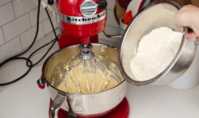 Adding the flour mixture to the cake batter for making a strawberry rhubarb cake.' title='Strawberry Rhubarb Crumb Cake