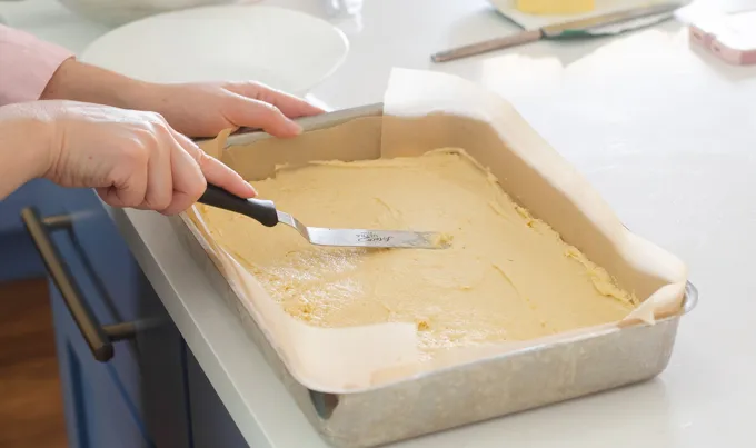 Spreading out the cake batter into the prepared pan with an offset spatula.' title='Strawberry Rhubarb Crumb Cake