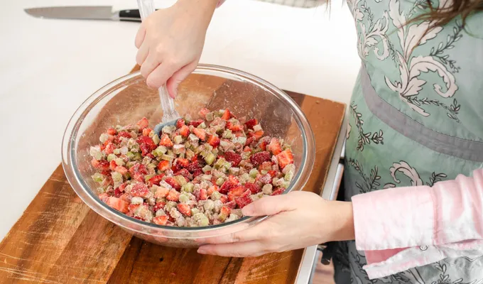 Tossing together the fruit filling ingredients.' title='Strawberry Rhubarb Crumb Cake