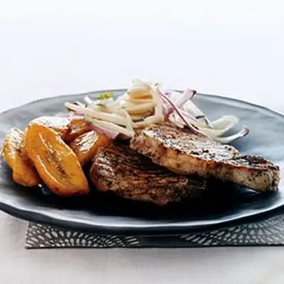 Costeleiros de porco com corações de salada de palmeira e bananas doces