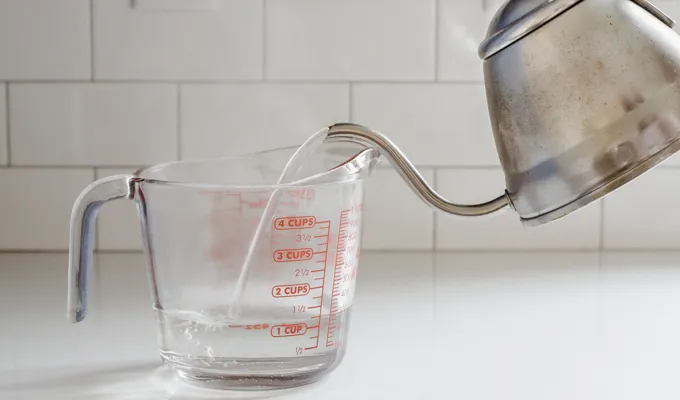 Pouring boiling water into a glass measuring cup.' title='Iced Chai Latte Recipe