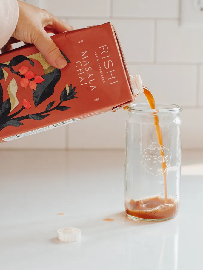Pouring chai concentrate into a cup to make an iced chai latte.' title='Iced Chai Latte Recipe