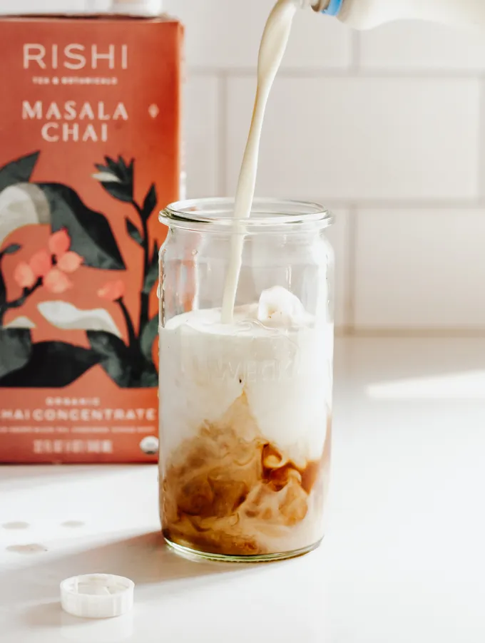 Pouring cream on top to make an iced chai tea latte.' title='Iced Chai Latte Recipe