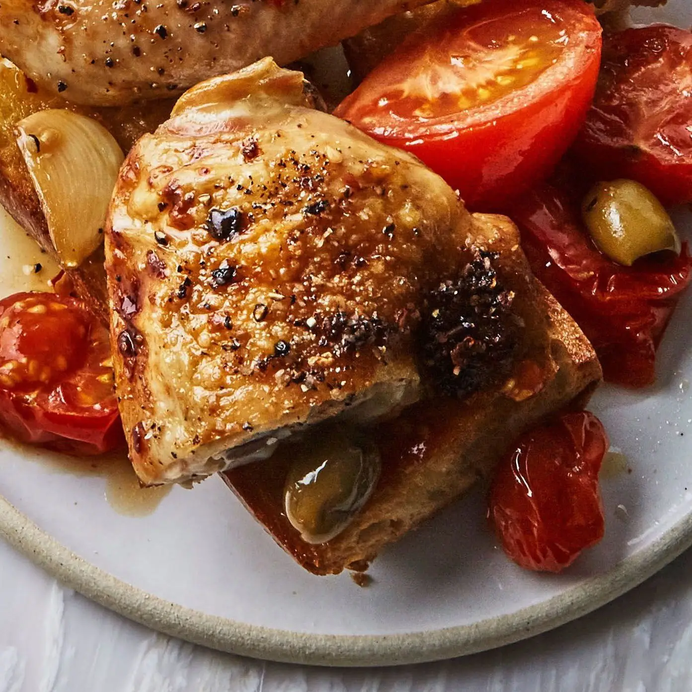 Frango assado de um lado com tomate e azeitonas