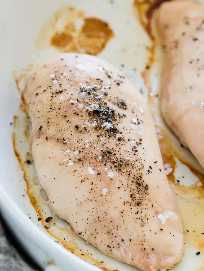 A close-up shot of a baked boneless skinless chicken breast with salt and pepper on top.' title='How to Bake Boneless Skinless Chicken Breasts