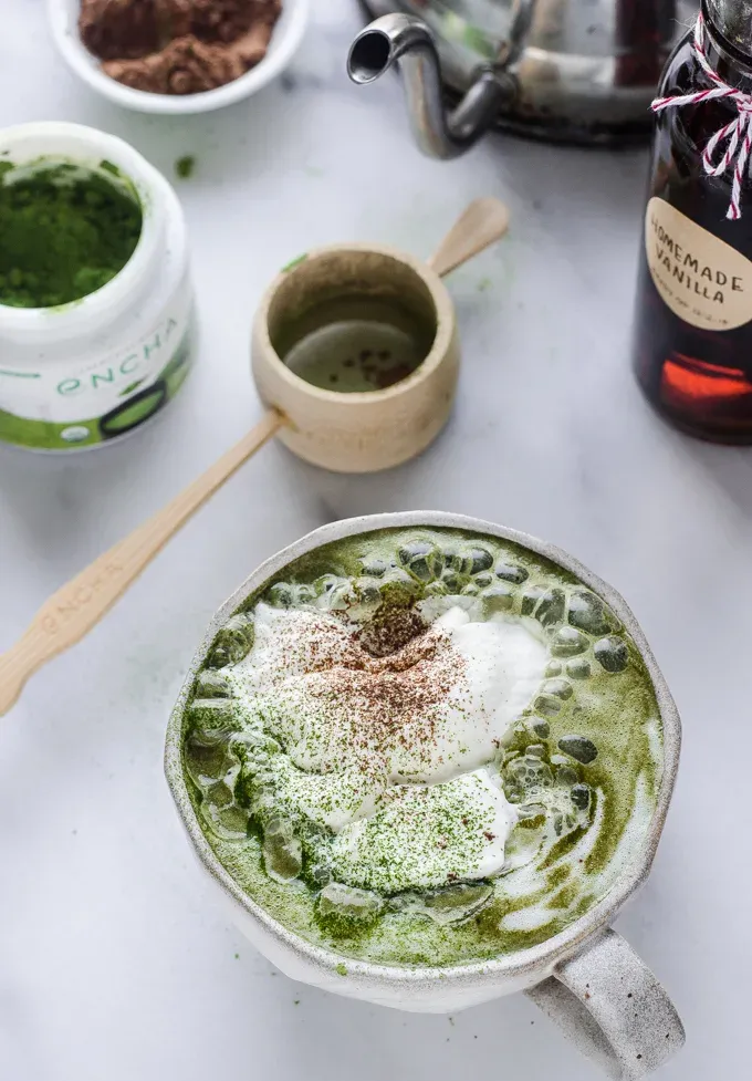 A mug of matcha cocoa with a tea kettle in the background.' title='Matcha Cocoa
