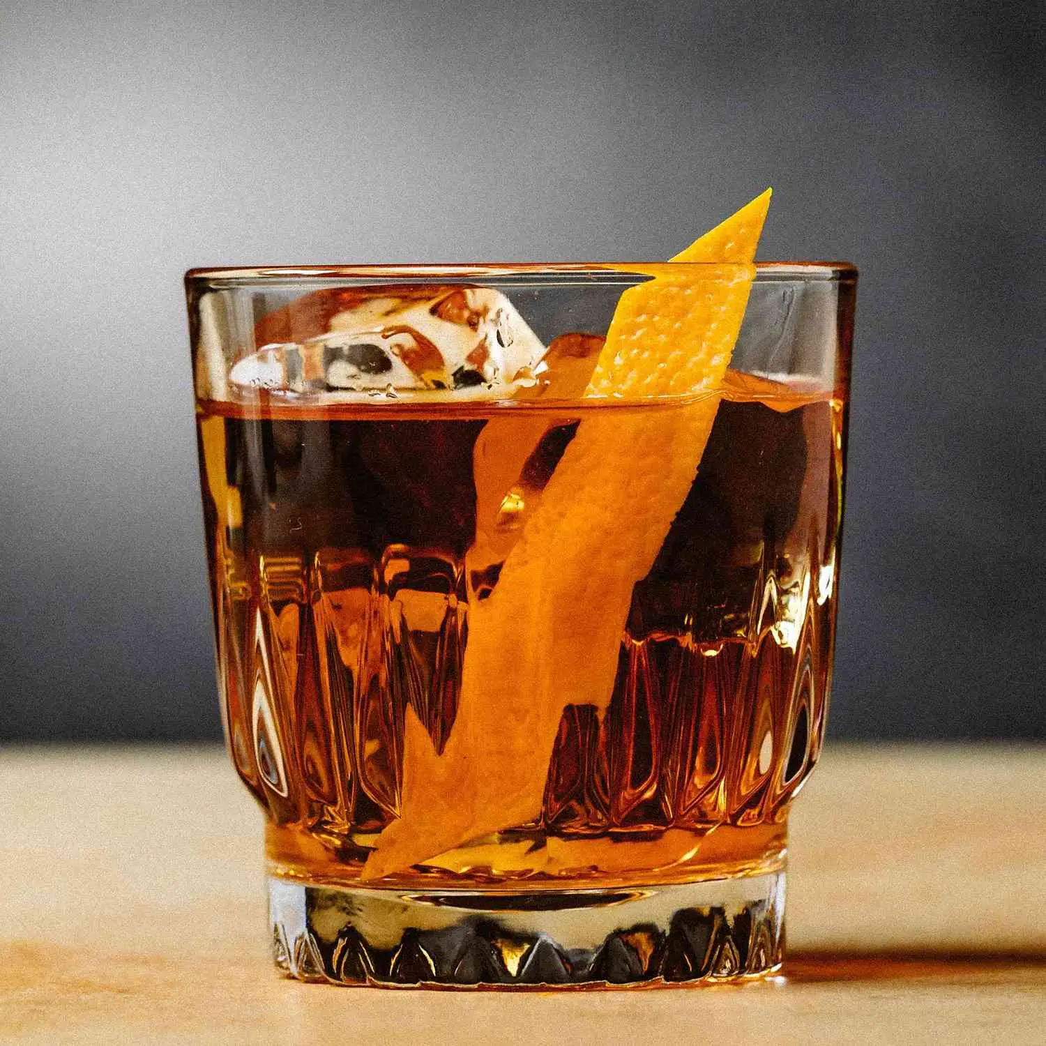 Autumn Rum Old Fashioned served in rocks glass with orange twist on wooden surface