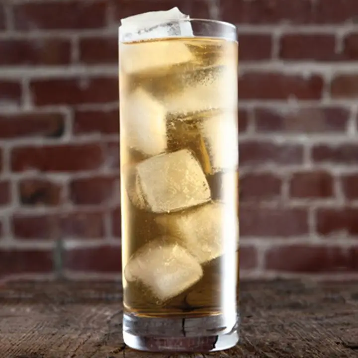 7&7 cocktail in a highball glass with several ice cubes, set against a red brick background