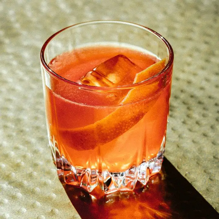 Grapefruit Negroni in a rocks glass, with one large ice cube and a large, wide grapefruit peel