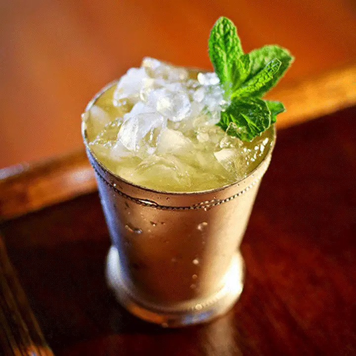 Kentucky Mule served in a copper mug and topped with a mint sprig garnish, served on a straw mat
