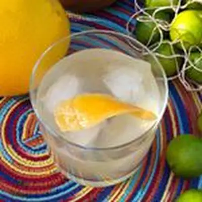 A birdseye view of a shaken cocktail in a rocks glass garnished with a manicured orange twist