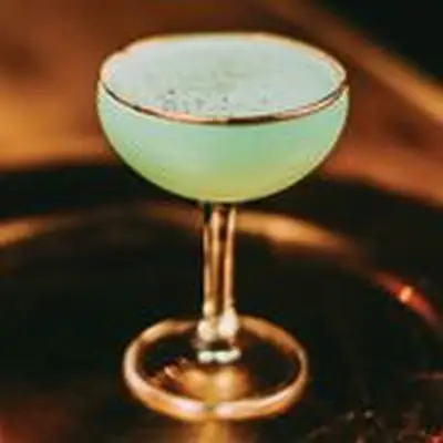 green-hued grasshopper cocktail in a gold-rimmed coupe glass