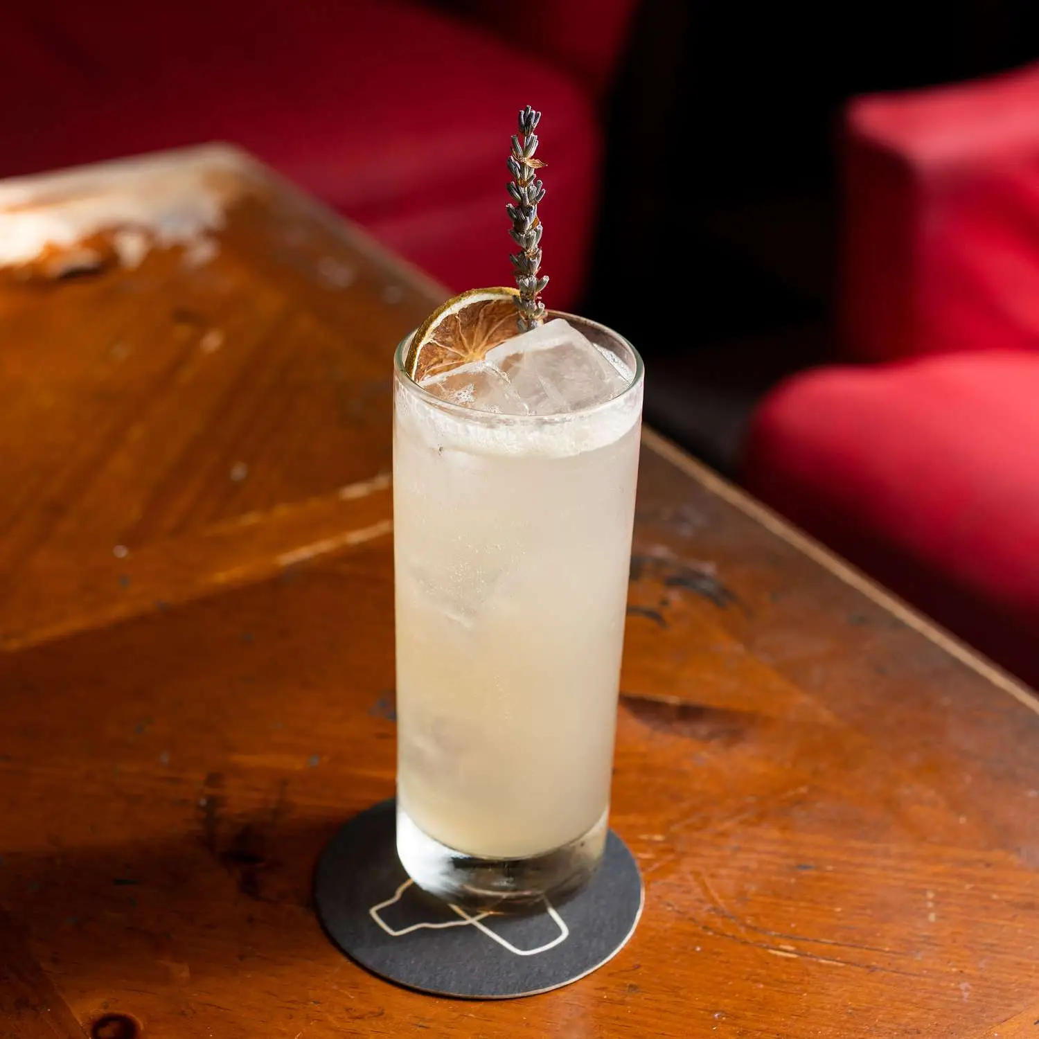 Lavender Mule in collins glass on coaster with lavender sprig and dehydrated orange wheel